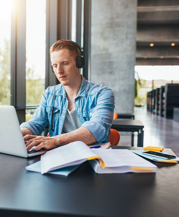 Ein Student arbeitet konzentriert am Laptop und symbolisiert die Anforderungen und Bed&uuml;rfnisse junger Talente bei der Verbindung von Studium und Beruf.