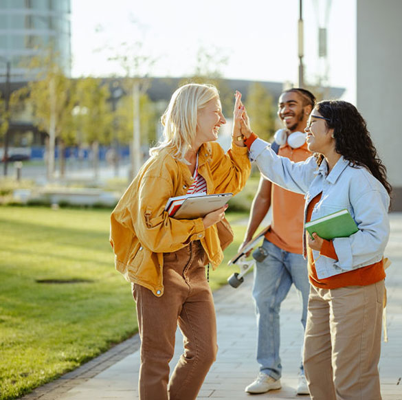 Mehrere Studierende stehen gemeinsam auf dem Campus, tauschen sich aus und freuen sich &uuml;ber einen gemeinsamen Erfolg.